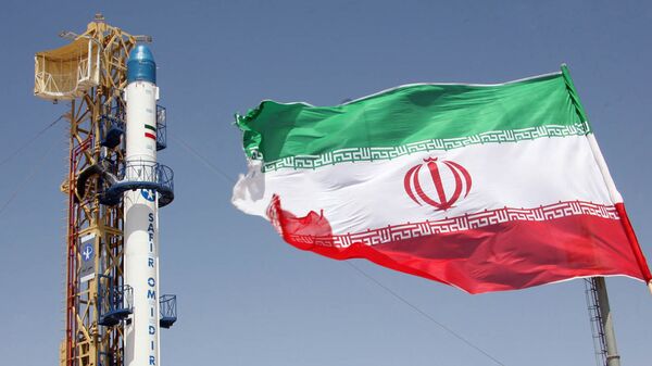 Iranian flag fluttering in front of Iran's Safir Omid rocket, which is capable of carrying a satellite into orbit, before it's launch in a space station at an undisclosed location in the Islamic Republic. File photo. - Sputnik International