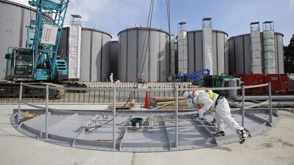 Men wearing protective suits and masks work in front of welding storage tanks for radioactive water, under construction in the J1 area at the Tokyo Electric Power Co's (TEPCO) tsunami-crippled Fukushima Daiichi nuclear power plant in Okuma in Fukushima prefecture. (File) - Sputnik International