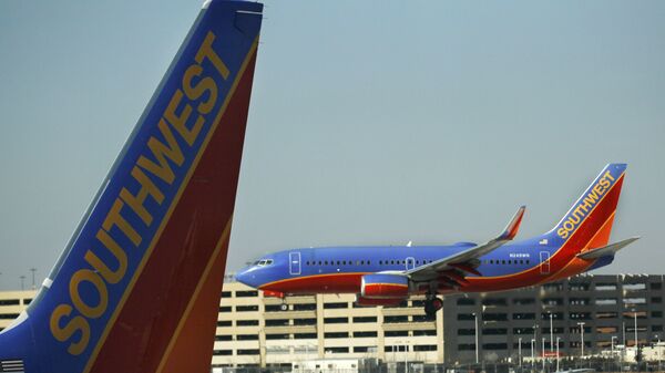 In this Feb. 9, 2012, a Southwest Airlines Boeing lands at Chicago's Midway Airport as another sits at a gate. Southwest Airlines Co. said Thursday, March 1, 2012, that it took a step toward combining its fleet with that of AirTran Airways as U.S. officials gave the airlines a single operating certificate - Sputnik International