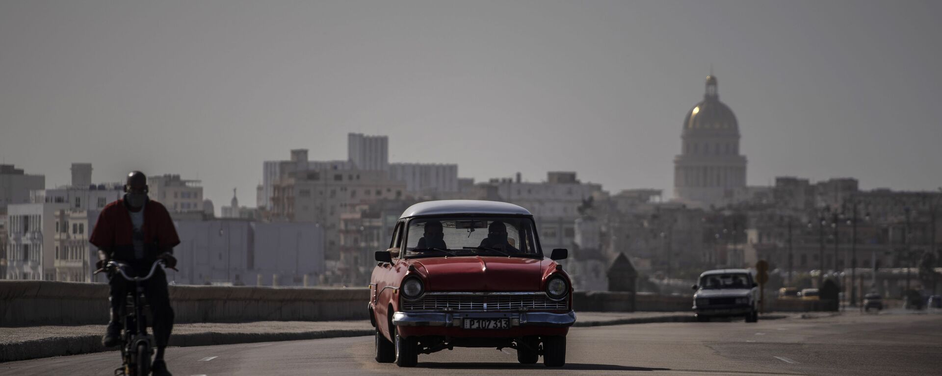 An American classic car and bicycle share the road on the Malecon amid a cloud of Sahara dust in Havana, Cuba, Thursday, June 25, 2020.  - Sputnik International, 1920, 20.06.2023