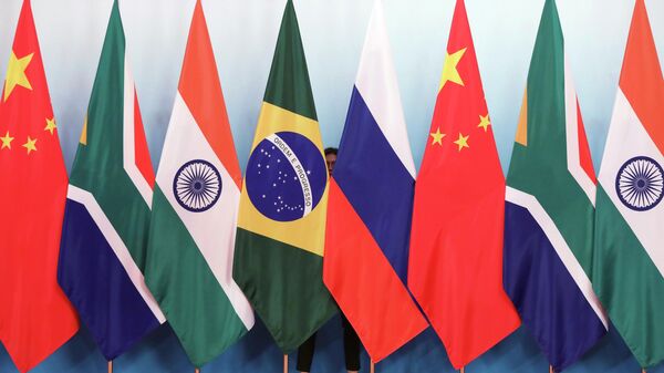 Staff worker stands behind national flags of Brazil, Russia, China, South Africa and India to tidy the flags ahead of a group photo during the BRICS Summit at the Xiamen International Conference and Exhibition Center in Xiamen, southeastern China's Fujian Province, Monday, Sept. 4, 2017. - Sputnik International