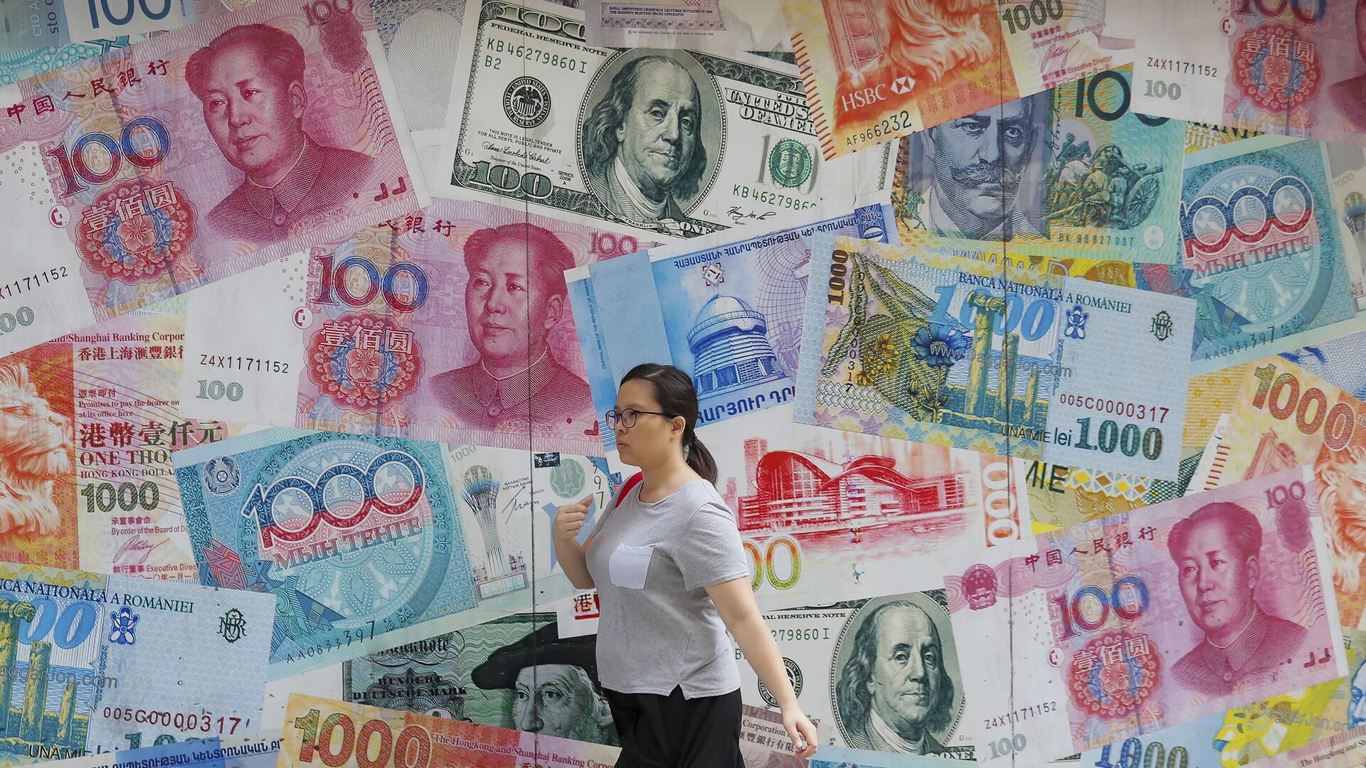  A woman walks by a money exchange shop decorated with different countries currency banknotes at Central, a business district in Hong Kong, Aug. 6, 2019. - Sputnik International, 1920, 24.08.2023
