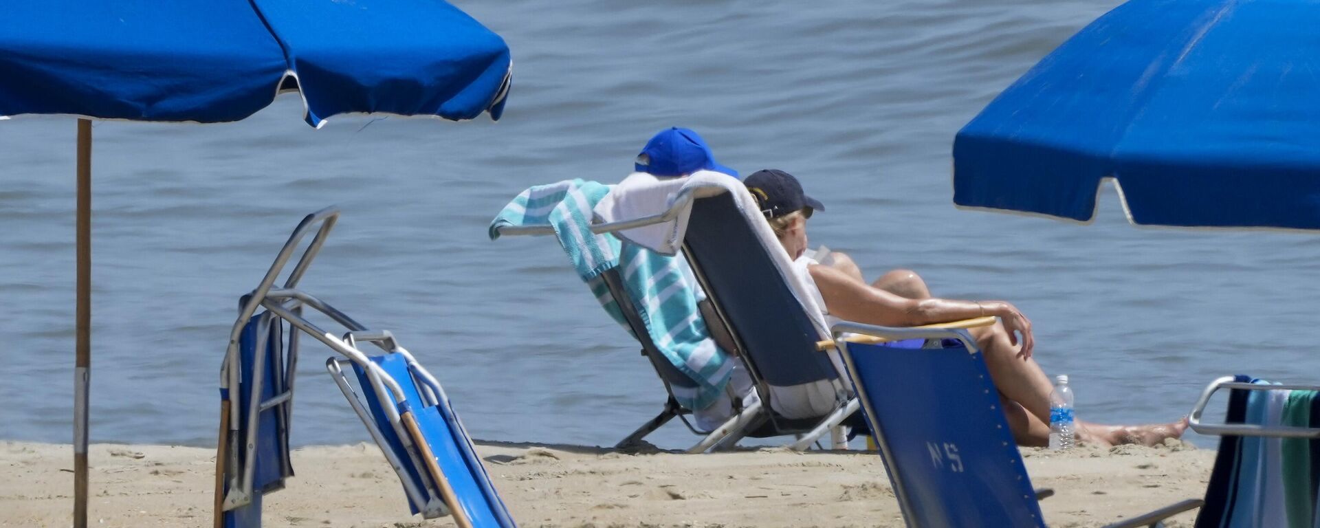 President Joe Biden, in blue hat, sits on the beach with first lady Jill Biden on Saturday, July 8, 2023, near his home in Rehoboth Beach, Del. - Sputnik International, 1920, 09.07.2023