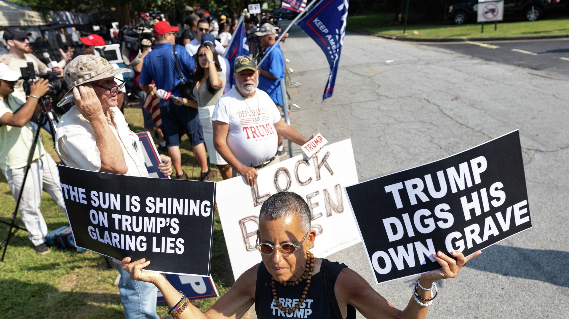 A counter protester waves anti-Trump signs outside the Fulton County Jail ahead of his expected arrival on August 24, 2023, in Atlanta, Georgia. Former US President Donald Trump and 18 others were given until August 25, 2023 to surrender at the courthouse after being indicted on 41 counts related to their efforts to overturn the 2020 US Presidential election. (Photo by Christian MONTERROSA / AFP) - Sputnik International, 1920, 24.08.2023